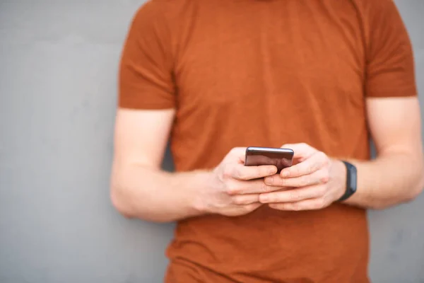 Junger Mann benutzt Smartphone in der Nähe einer schlampig bemalten grauen Stadtmauer — Stockfoto