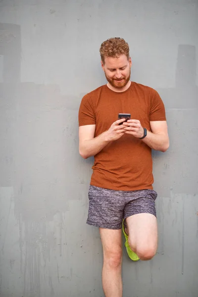 Junger Mann benutzt Smartphone in der Nähe einer schlampig bemalten grauen Stadtmauer — Stockfoto