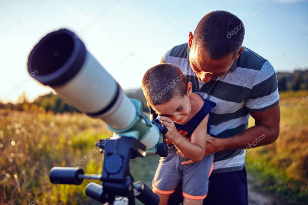 Father and son observing the sky with a telescope.