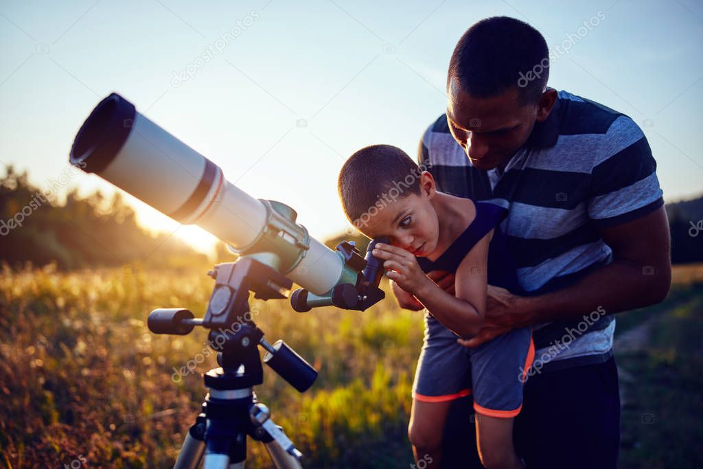 Father and son observing the sky with a telescope.