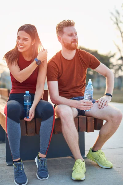 Pareja moderna haciendo una pausa en un parque urbano durante el jogging / exe — Foto de Stock