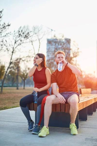 Casal moderno fazendo pausa em um parque urbano durante jogging / exe — Fotografia de Stock