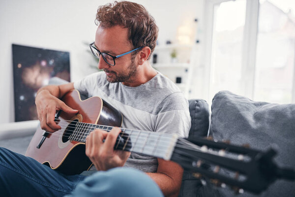 Man playing acoustic guitar in the living room.