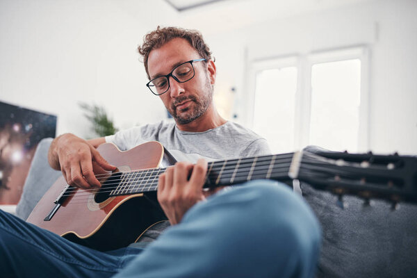 Man playing acoustic guitar in the living room.