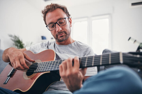 Man playing acoustic guitar in the living room.