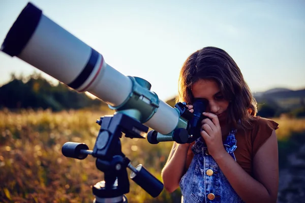 Küçük kız evreni keşfetmek için doğada teleskop kullanıyor.. — Stok fotoğraf