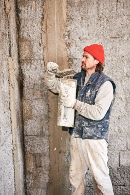 Gerçek inşaat işçisi yeni evin içinde bir duvar yapma.