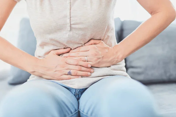 Mujer con problemas de estómago / problemas mientras está acostada en el sofá . —  Fotos de Stock