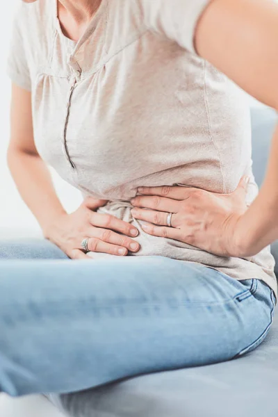 Mujer con problemas de estómago / problemas mientras está acostada en el sofá . —  Fotos de Stock