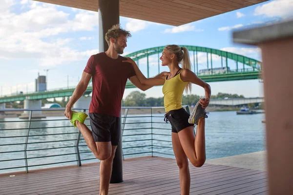 Modern woman and man exercising in urban surroundings near the r — Stock Photo, Image