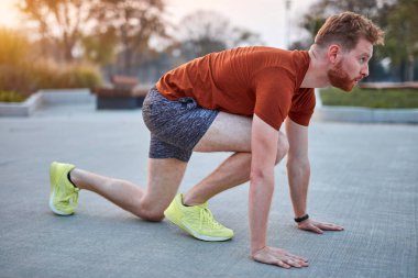 Genç modern adam şehir parkında koşuyor / egzersiz yapıyor.