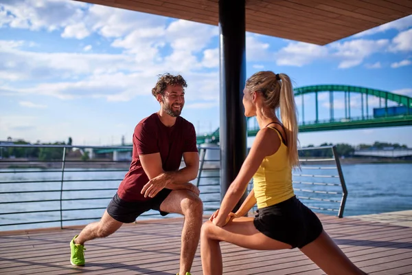 Modern woman and man exercising in urban surroundings near the r — Stock Photo, Image