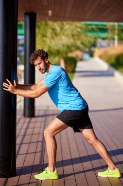 Kentsel çevrede esneyen ve egzersiz yapan bir adam.