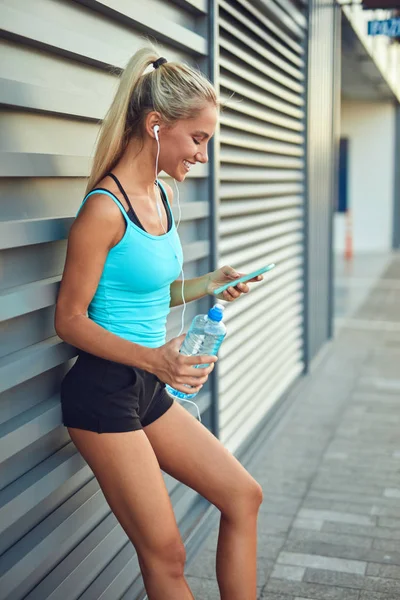 Deportiva moderna haciendo una pausa después de trotar en el área urbana . — Foto de Stock