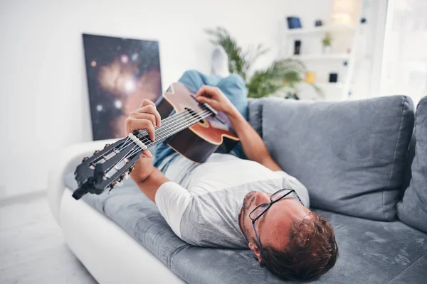 Man spelar akustisk gitarr i vardagsrummet. — Stockfoto