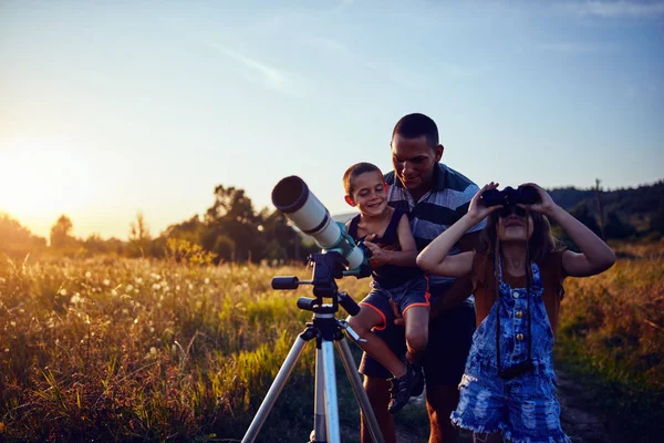 Vater, Tochter und Sohn beobachten den Himmel mit dem Teleskop. — Stockfoto