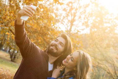 Genç çift sonbahar renkli park'cep telefonu kullanma.