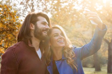 Genç çift sonbahar renkli park'cep telefonu kullanma.