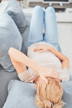 Kanepede yatarken mide sorunları olan bir kadın..