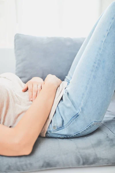 Жінка з проблемами шлунку / проблемами лежачи на дивані . — стокове фото