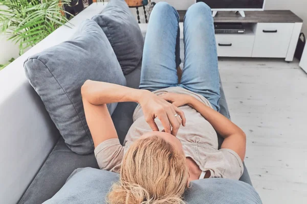 Mujer con problemas de estómago / problemas mientras está acostada en el sofá . — Foto de Stock