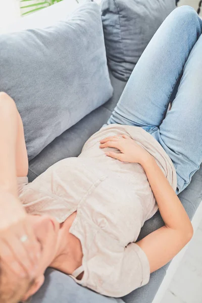 Женщина с проблемами с желудком, лежа на диване . — стоковое фото