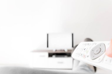 Oturma odasında bacakları masanın üstünde televizyona bakan bir adam..