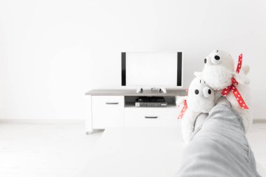 Oturma odasında bacakları masanın üstünde televizyona bakan bir kadın..