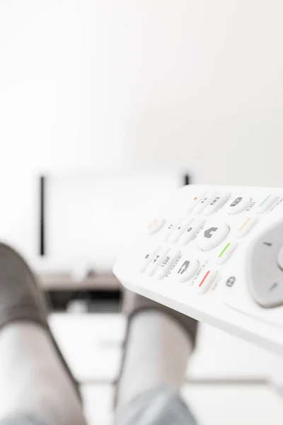 Hombre mirando TV con piernas en la mesa en la sala de estar . — Foto de Stock