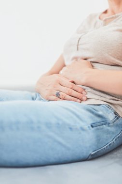 Kanepede yatarken mide sorunları olan bir kadın..