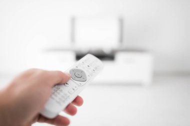 Modern bir televizyonla el ele tutuşan uzaktan kumanda..