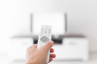 Modern bir televizyonla el ele tutuşan uzaktan kumanda..
