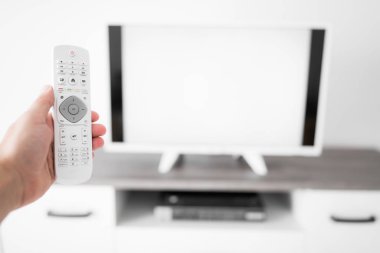 Modern bir televizyonla el ele tutuşan uzaktan kumanda..