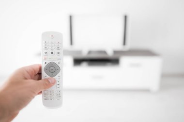 Modern bir televizyonla el ele tutuşan uzaktan kumanda..