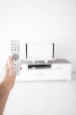Modern bir televizyonla el ele tutuşan uzaktan kumanda..