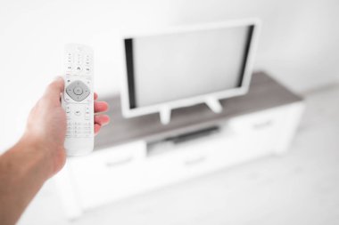 Modern bir televizyonla el ele tutuşan uzaktan kumanda..