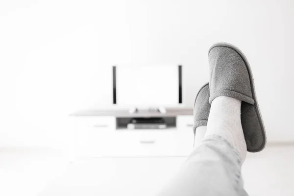 Hombre mirando TV con piernas en la mesa en la sala de estar . — Foto de Stock