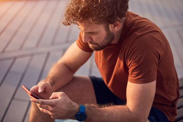 Junger erwachsener Mann mit modernem Handy im Park. — Stockfoto