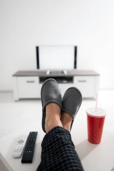 Hombre bebiendo jugo de soda y mirando televisión con piernas en la mesa — Foto de Stock