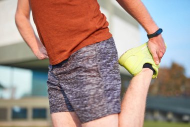 Genç adam şehir parkında egzersiz yapıyor / esniyor.