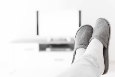 Oturma odasında bacakları masanın üstünde televizyona bakan bir adam..