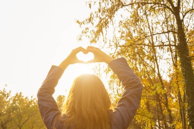 Elleriyle kalp yapan genç bir kadın..