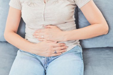 Kanepede yatarken mide sorunları olan bir kadın..