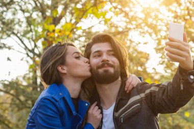 Genç çift sonbahar renkli park'cep telefonu kullanma.