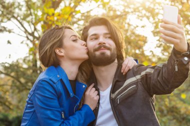 Genç çift sonbahar renkli park'cep telefonu kullanma.