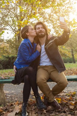 Genç çift sonbahar renkli park'cep telefonu kullanma.