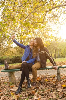 Genç çift sonbahar renkli park'cep telefonu kullanma.