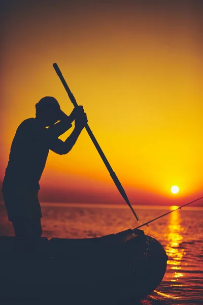 Silhouette d'un pêcheur pêchant au coucher du soleil en pleine mer — Photo