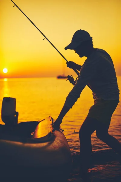 Silhouette d'un pêcheur pêchant au coucher du soleil en pleine mer — Photo