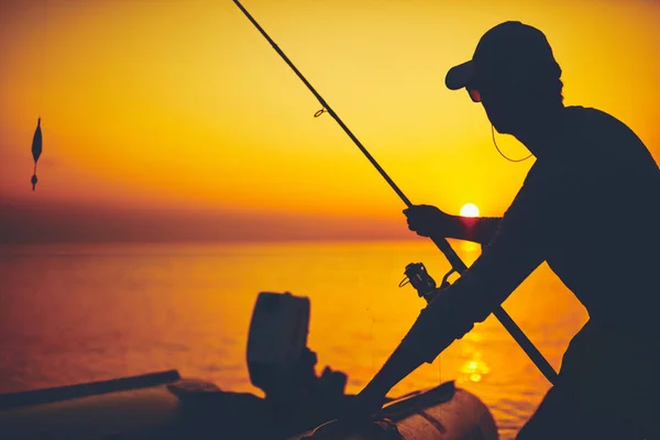 Silhueta de um pescador pescando em tempo de pôr do sol no mar aberto — Fotografia de Stock